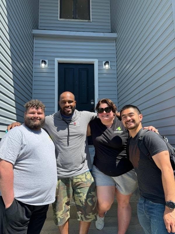 Four people smiling together outside a home