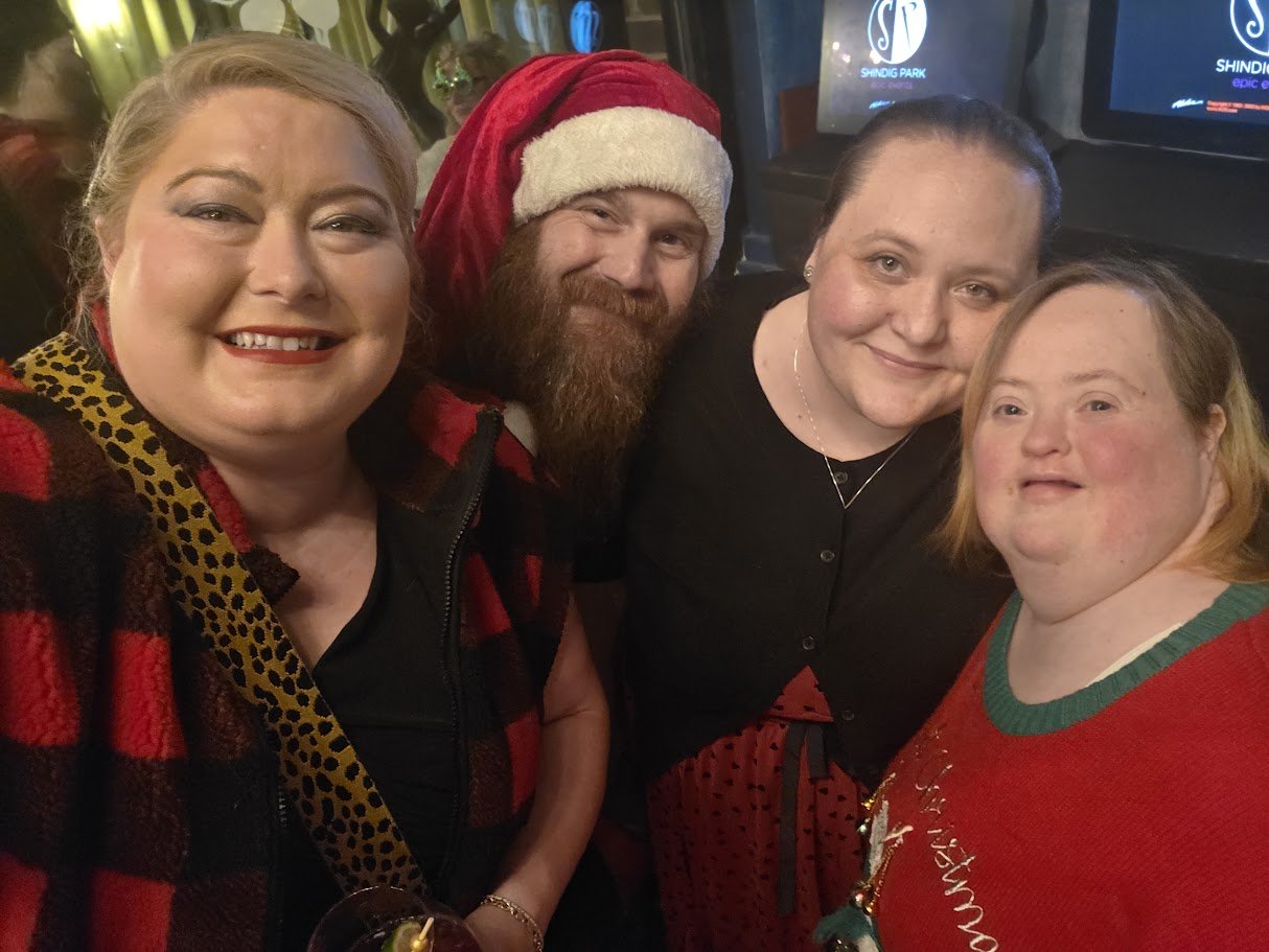 Four people smiling together during a holiday gathering