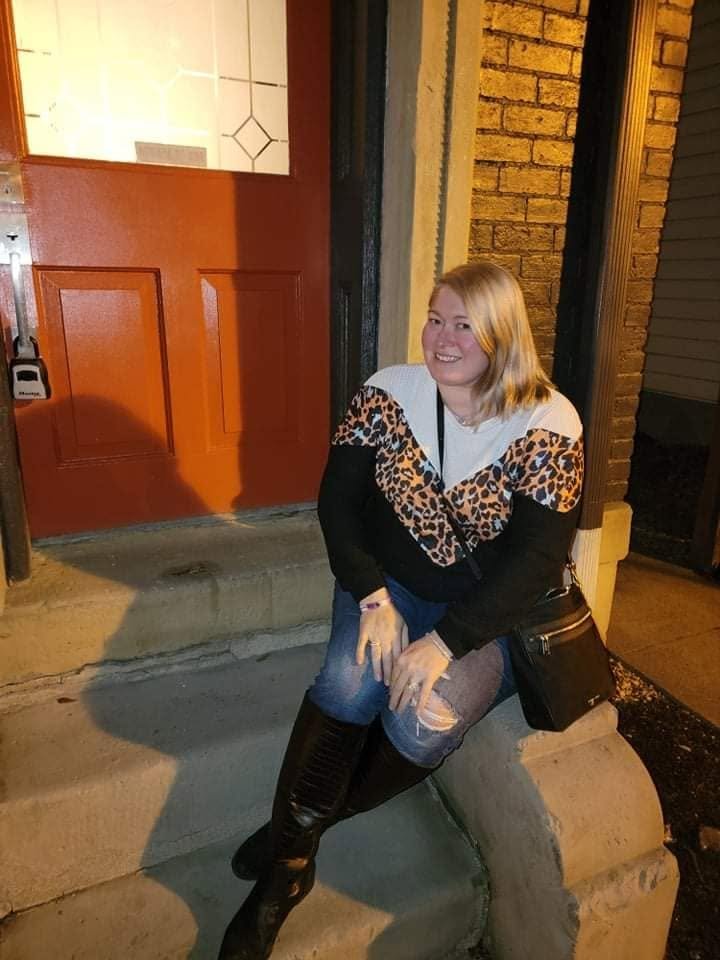 A woman sitting on the steps outside a brick building