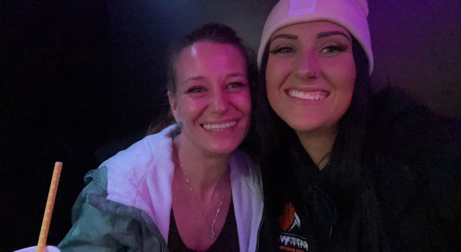 Two women smiling together under event lighting