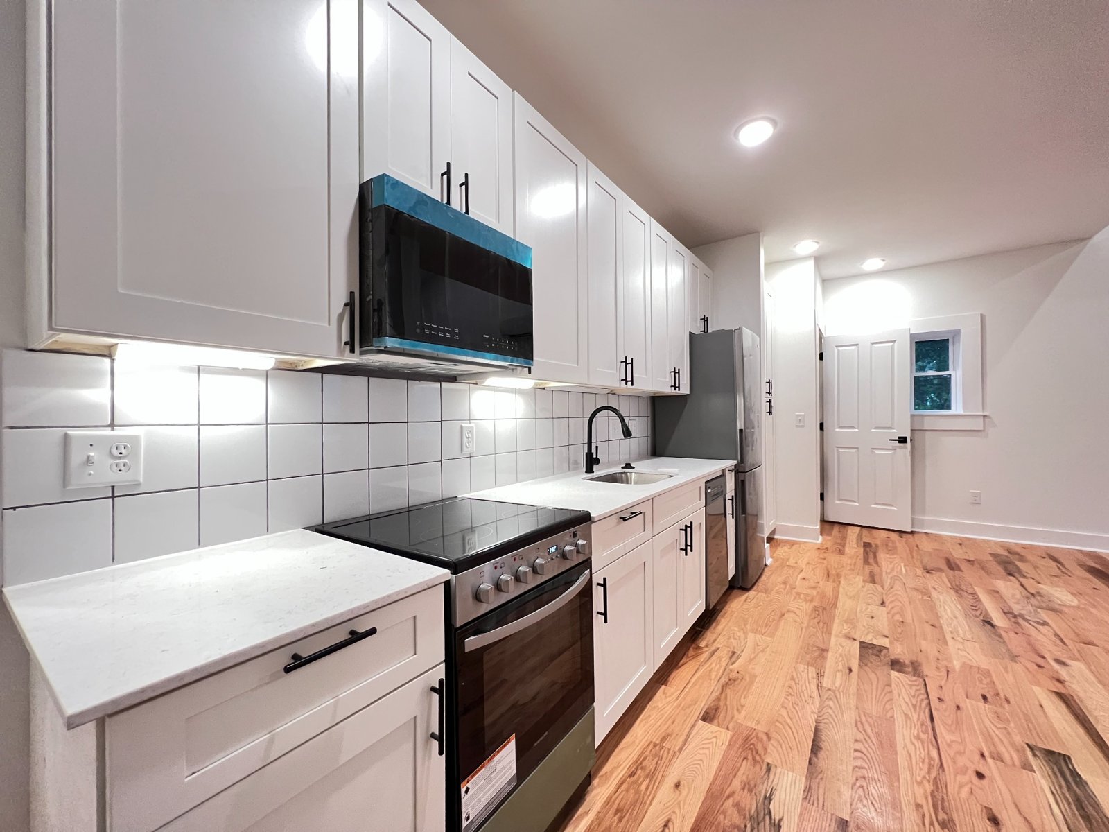 Bright kitchen with white cabinets, stainless steel appliances, and hardwood floors
