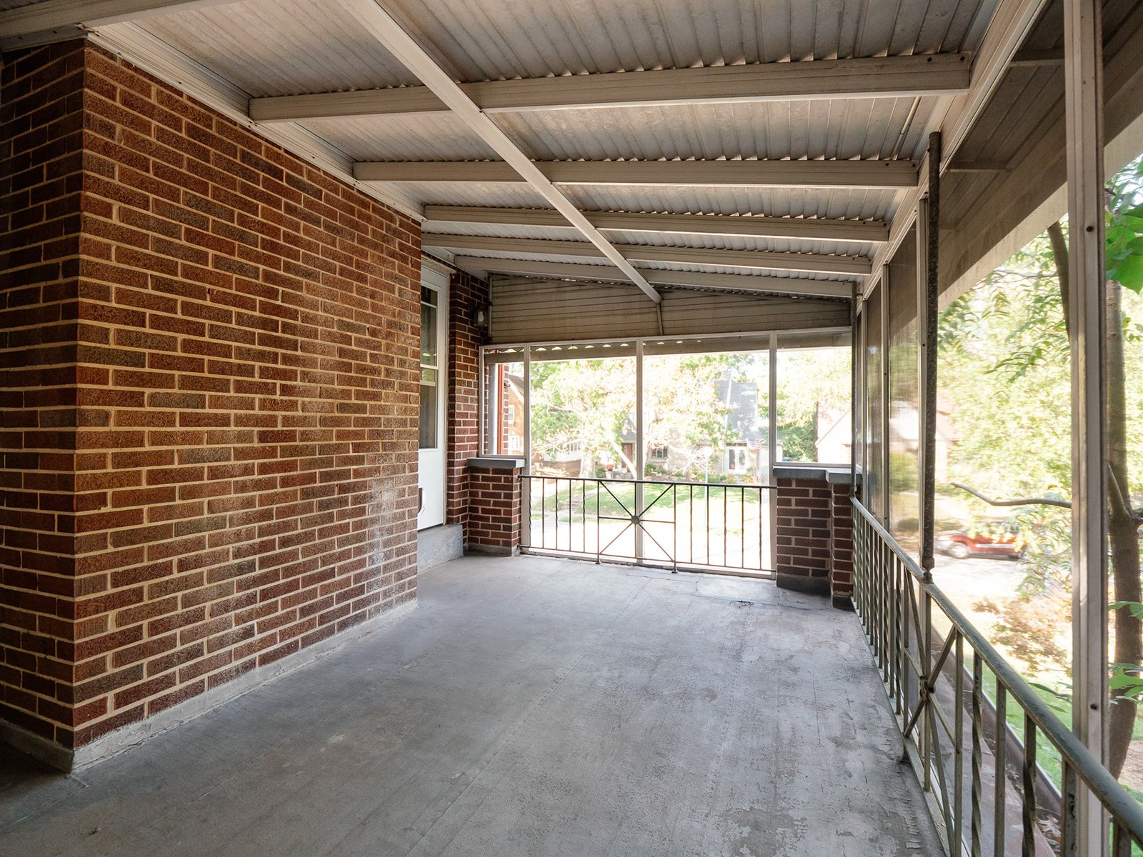 Screened porch with brick walls overlooking a leafy neighborhood